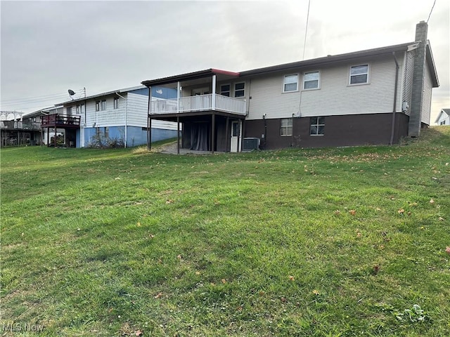 back of property with a balcony, cooling unit, and a lawn