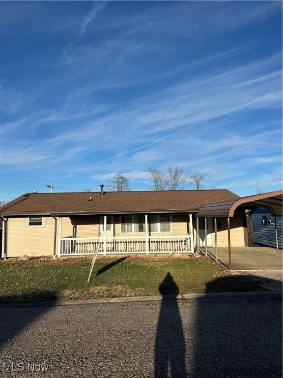 ranch-style home with covered porch, a front lawn, and a carport