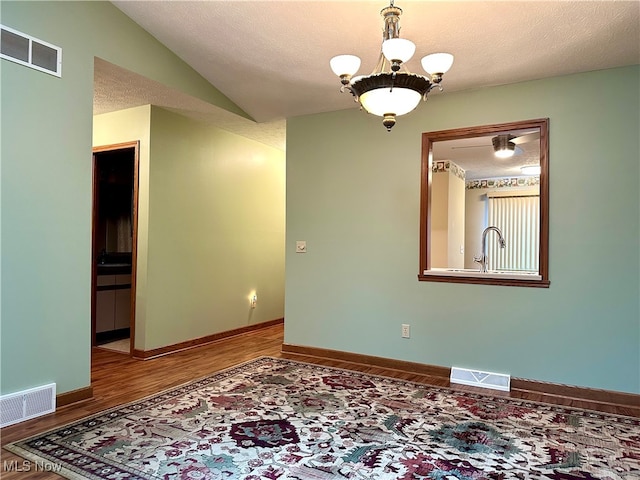 spare room with an inviting chandelier, a textured ceiling, and hardwood / wood-style flooring