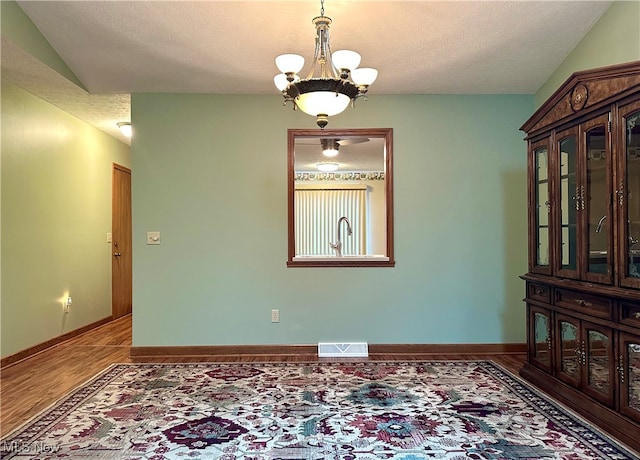 unfurnished room featuring wood-type flooring, a textured ceiling, and a chandelier