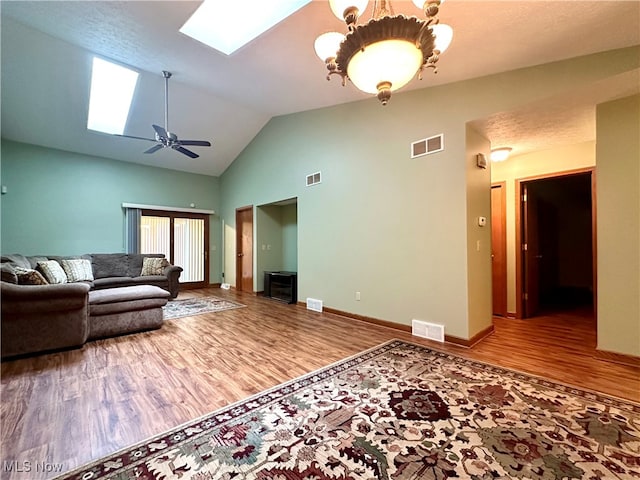 living room with hardwood / wood-style floors, ceiling fan, high vaulted ceiling, and a skylight