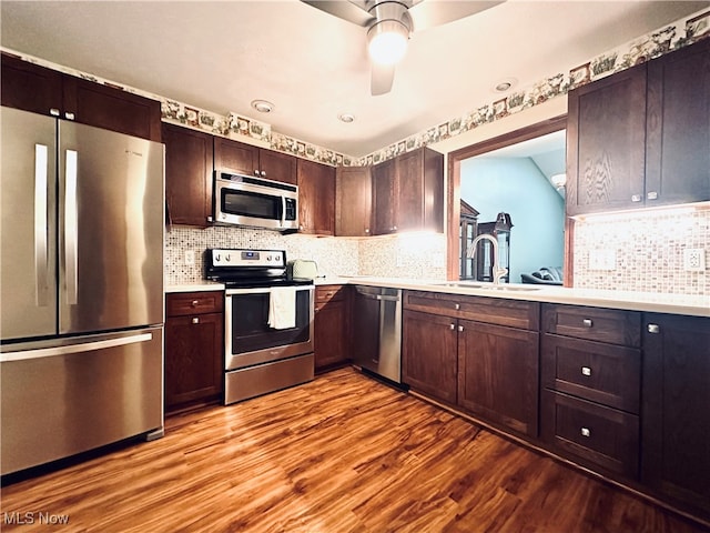 kitchen with decorative backsplash, dark brown cabinets, stainless steel appliances, sink, and light hardwood / wood-style flooring