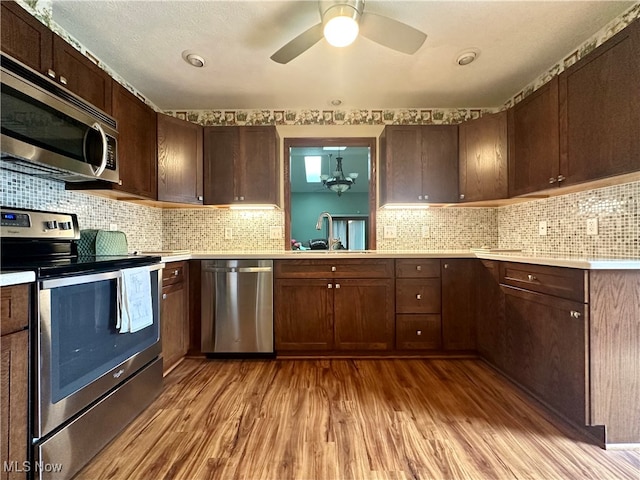 kitchen featuring decorative backsplash, appliances with stainless steel finishes, dark brown cabinetry, sink, and light hardwood / wood-style flooring