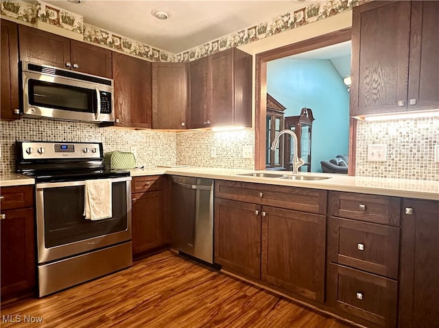 kitchen with dark brown cabinetry, sink, dark hardwood / wood-style flooring, backsplash, and appliances with stainless steel finishes