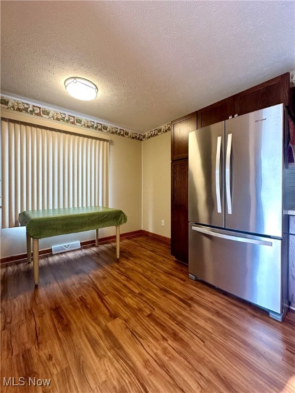 kitchen with hardwood / wood-style flooring, a textured ceiling, and stainless steel refrigerator