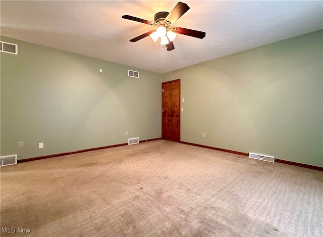 empty room featuring ceiling fan, light colored carpet, and a textured ceiling