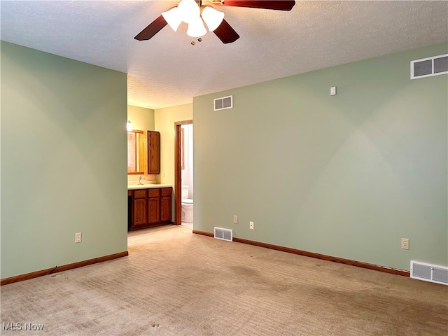 carpeted empty room with ceiling fan, sink, and a textured ceiling