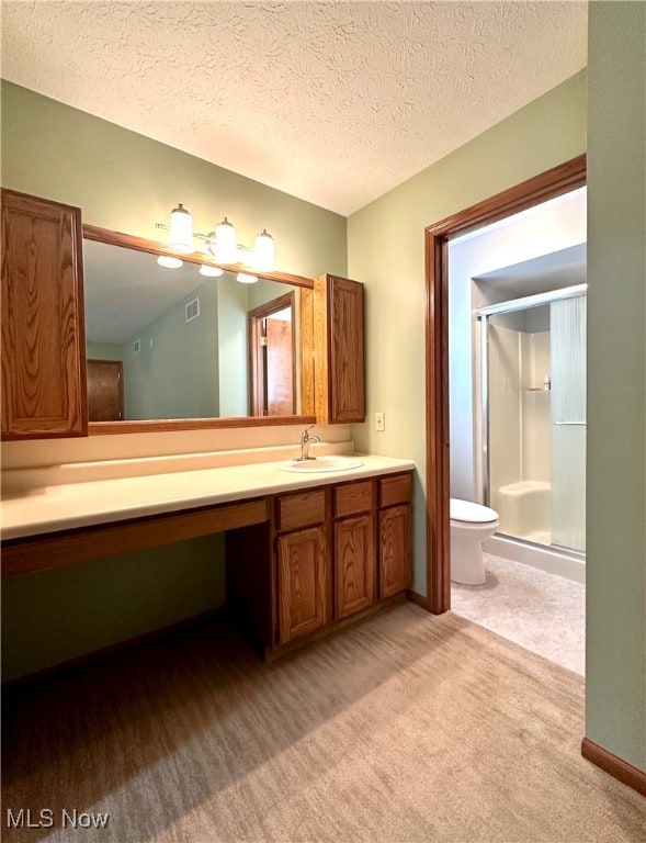 bathroom featuring a shower with door, vanity, a textured ceiling, and toilet