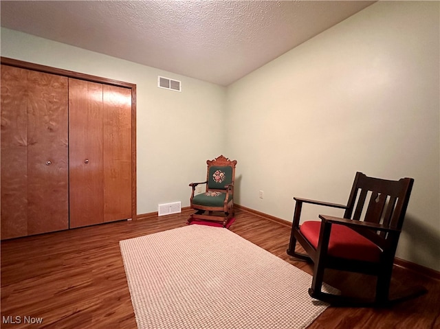 living area with hardwood / wood-style flooring, a textured ceiling, and vaulted ceiling