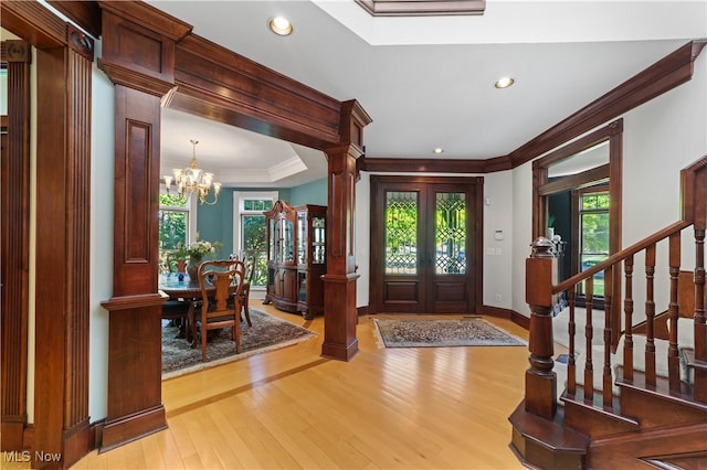 entryway with plenty of natural light, an inviting chandelier, crown molding, and light hardwood / wood-style flooring