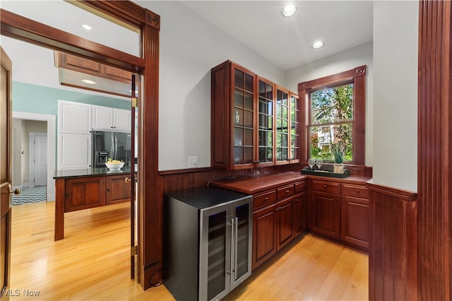 bar featuring wine cooler, light hardwood / wood-style flooring, and stainless steel refrigerator with ice dispenser