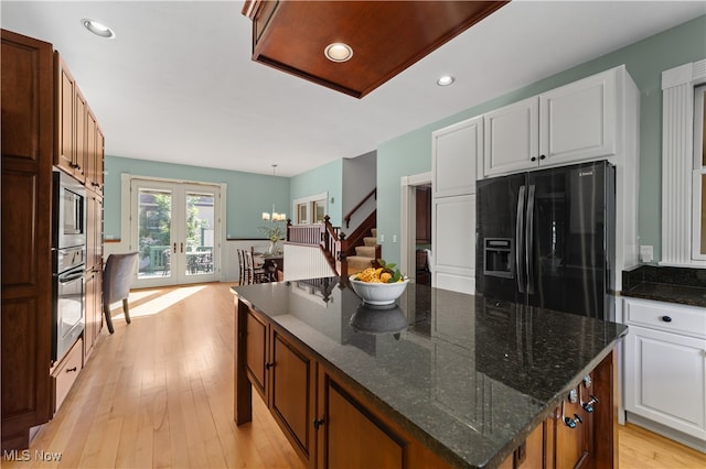 kitchen with white cabinetry, black refrigerator with ice dispenser, french doors, and a kitchen island