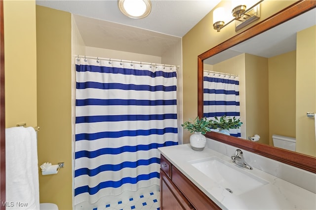 bathroom featuring a shower with shower curtain, vanity, and toilet