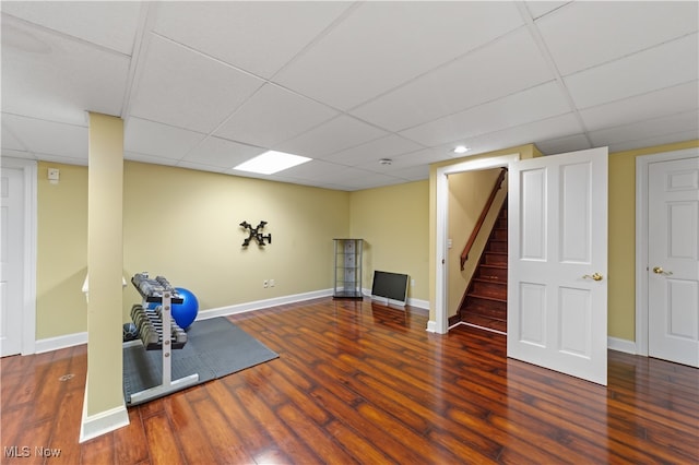 workout area with dark hardwood / wood-style flooring and a drop ceiling