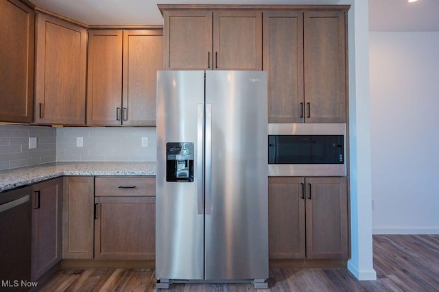 kitchen featuring backsplash, light stone countertops, dark hardwood / wood-style flooring, and appliances with stainless steel finishes