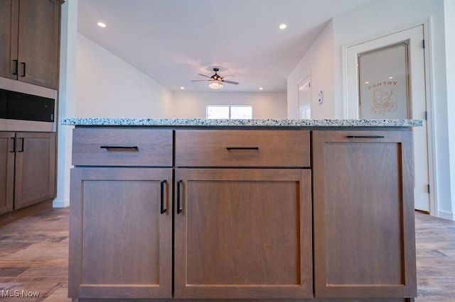 kitchen featuring ceiling fan, light hardwood / wood-style floors, and light stone counters