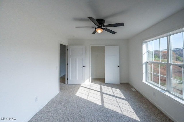 unfurnished bedroom featuring ceiling fan, light colored carpet, and a closet