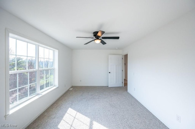 empty room with carpet flooring, ceiling fan, and plenty of natural light