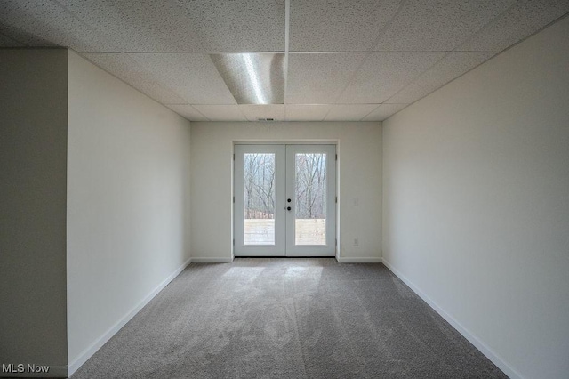 empty room with carpet, a paneled ceiling, and french doors