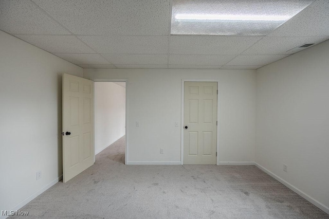 carpeted empty room featuring a paneled ceiling