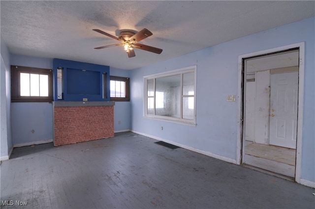 unfurnished living room featuring ceiling fan, hardwood / wood-style floors, a healthy amount of sunlight, and a textured ceiling