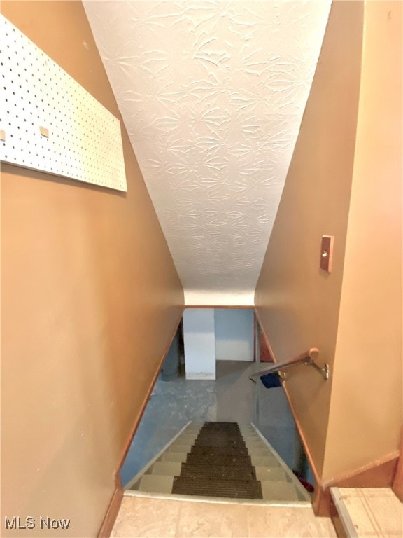 staircase with a textured ceiling and lofted ceiling