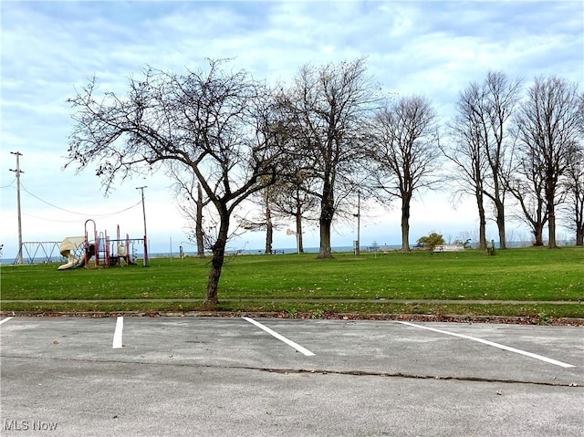 view of vehicle parking featuring a yard and a playground