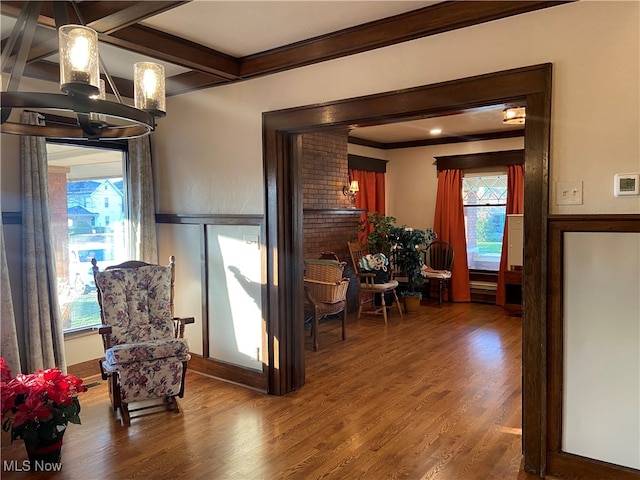 living area with hardwood / wood-style flooring, crown molding, and beamed ceiling