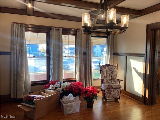 living area featuring hardwood / wood-style floors, beamed ceiling, and an inviting chandelier