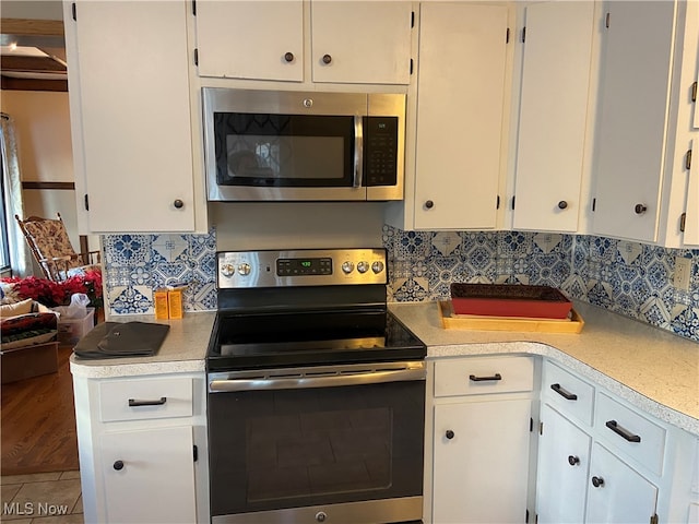 kitchen featuring stainless steel appliances, white cabinetry, and tasteful backsplash