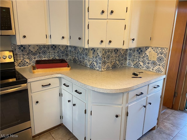 kitchen with backsplash, white cabinetry, light tile patterned floors, and stainless steel appliances