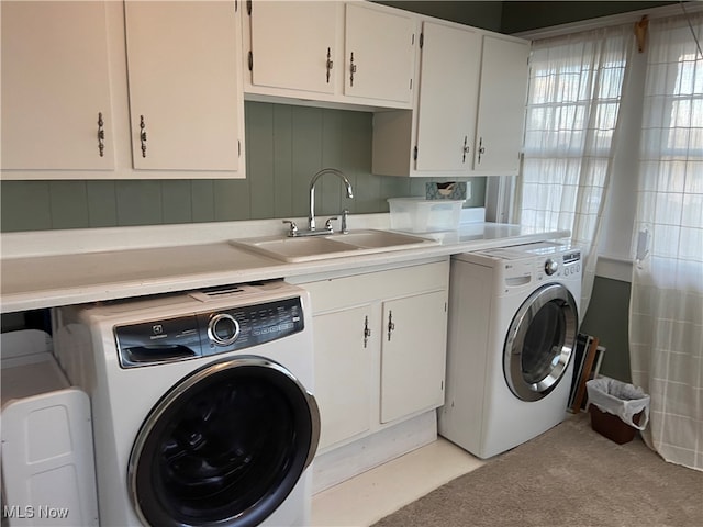 washroom with cabinets, independent washer and dryer, and sink