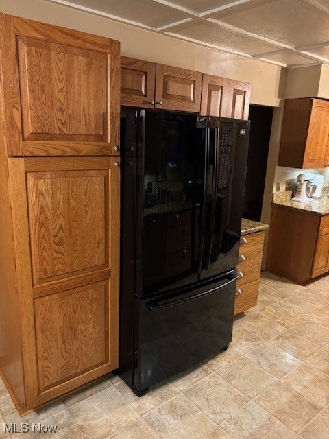 kitchen with black refrigerator and light stone counters