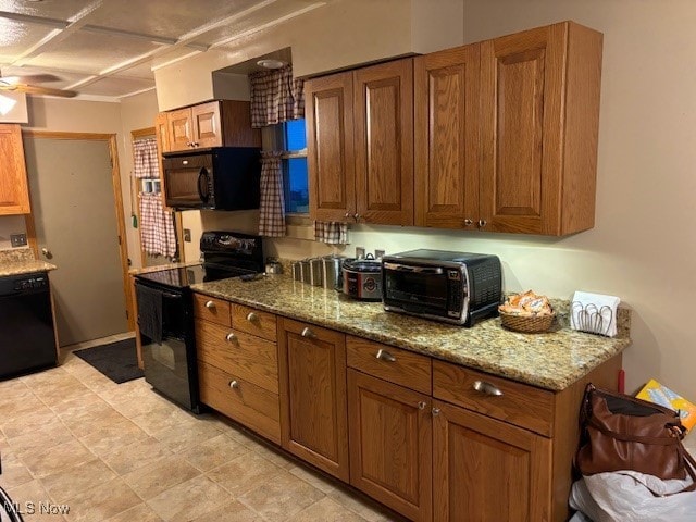 kitchen featuring light stone countertops, ceiling fan, and black appliances