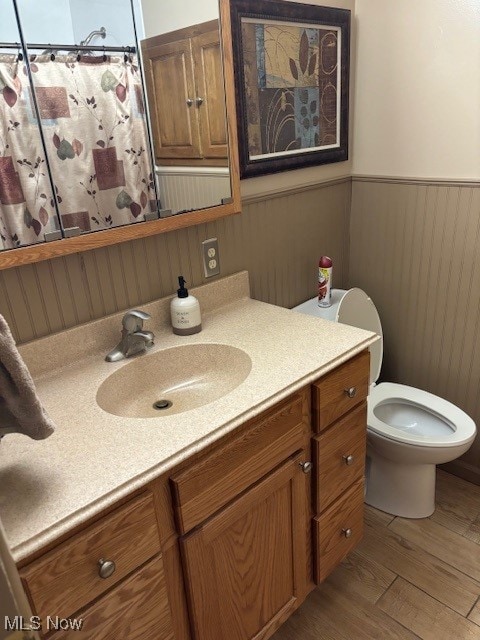 bathroom with wood walls, hardwood / wood-style floors, vanity, and toilet