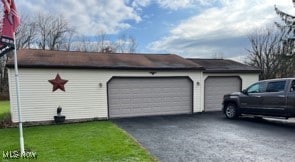 view of property exterior with an outbuilding, a garage, and a lawn