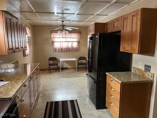 kitchen with black fridge, light stone countertops, and ceiling fan