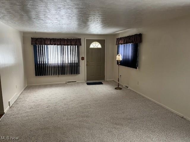 carpeted foyer entrance featuring a textured ceiling