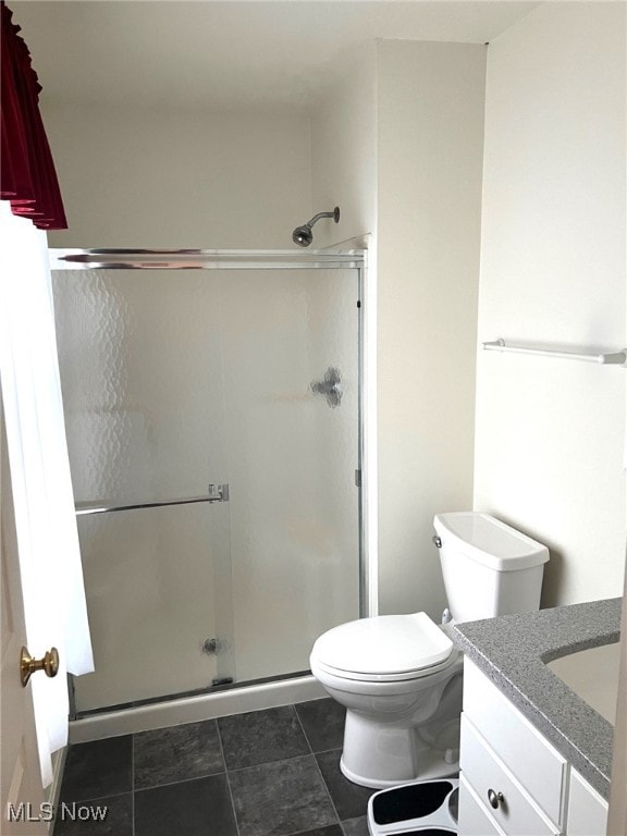 bathroom featuring tile patterned floors, toilet, vanity, and walk in shower