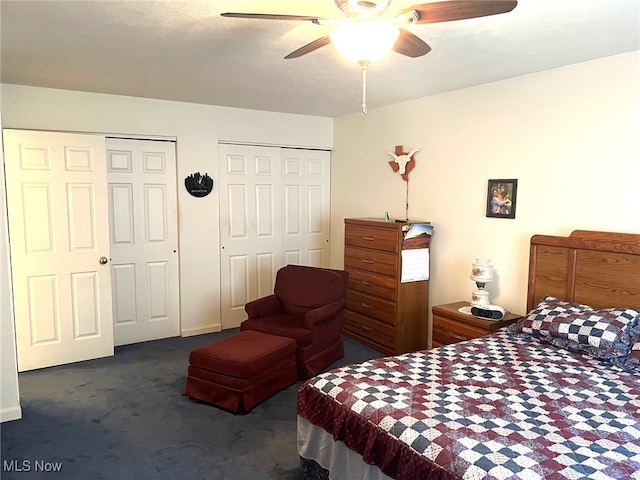 bedroom with dark colored carpet, ceiling fan, and multiple closets