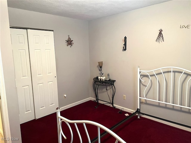 carpeted bedroom featuring a textured ceiling and a closet