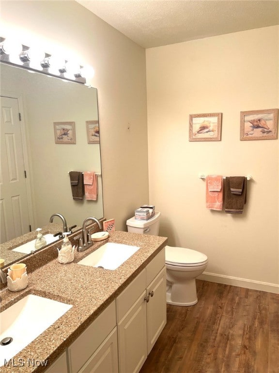 bathroom featuring wood-type flooring, vanity, a textured ceiling, and toilet