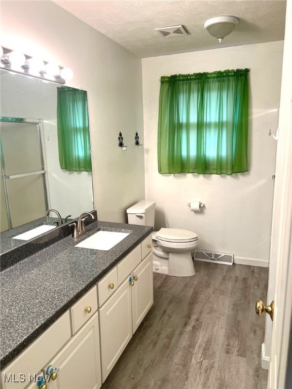 bathroom with hardwood / wood-style floors, vanity, toilet, and a textured ceiling