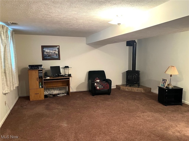 interior space with dark carpet, a wood stove, and a textured ceiling