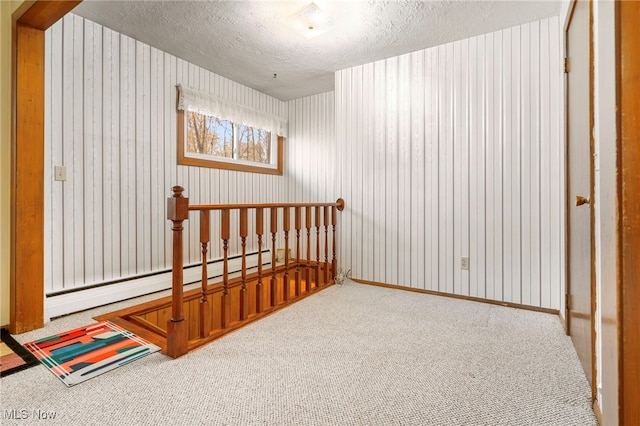 additional living space featuring carpet, a baseboard radiator, and a textured ceiling