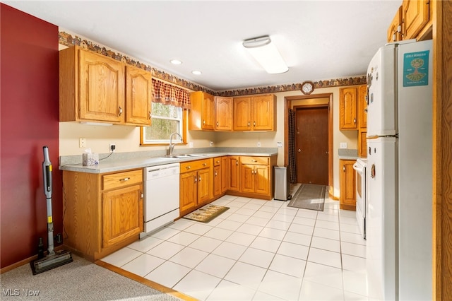 kitchen featuring light tile patterned floors, white appliances, and sink