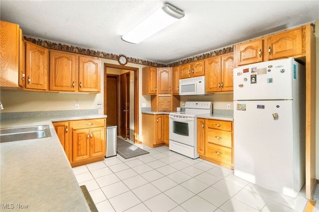 kitchen with light tile patterned flooring, white appliances, and sink