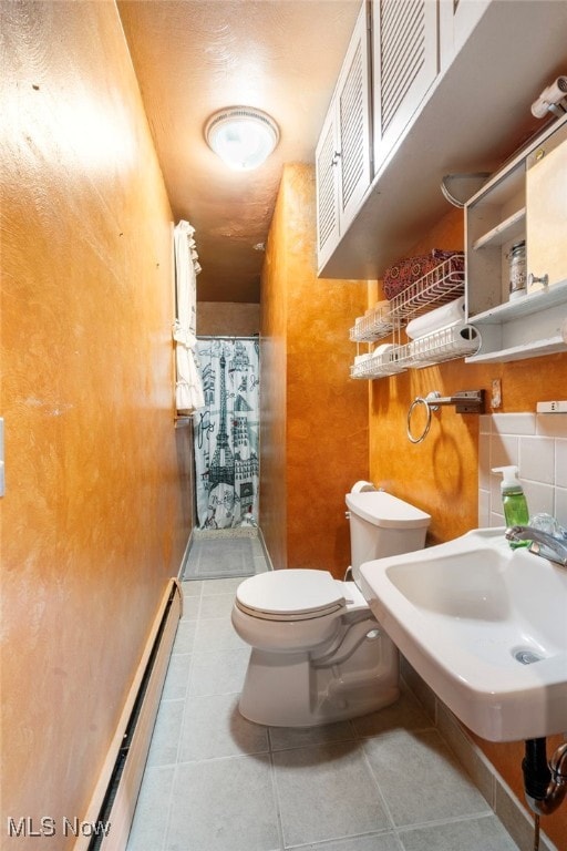 bathroom featuring tile patterned flooring, curtained shower, a baseboard heating unit, and sink