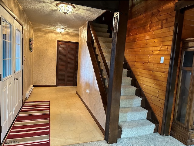 stairs featuring a textured ceiling and a baseboard heating unit