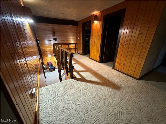 hall featuring carpet floors and wooden walls